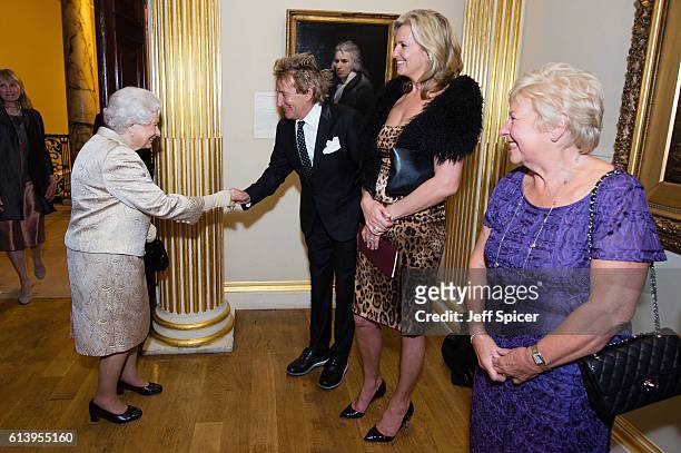 Queen Elizabeth II greets Sir Rod Stewart and wife Penny Lancaster after he was awarded a knighthood in recognition of his services to music and...