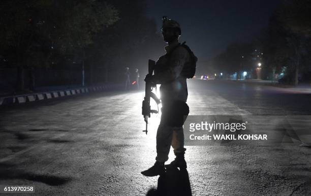 An Afghan security personnel walks as he keep watch near the site of an attack by gunmen inside the Kart-e- Sakhi shrine in Kabul on October 11,...
