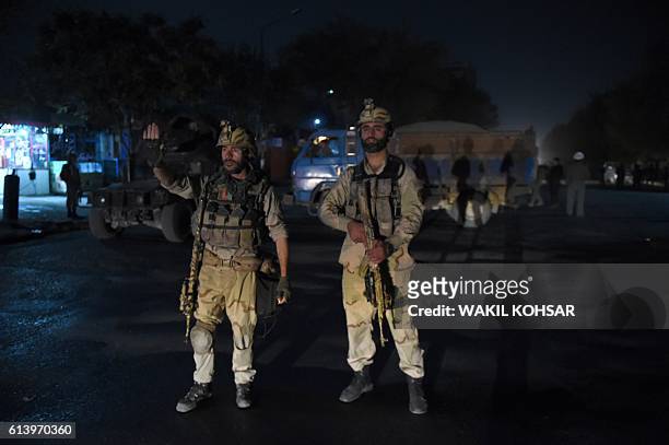 Afghan security personnels stands as they keep watch near the site of an attack by gunmen inside the Kart-e- Sakhi shrine in Kabul on October 11,...