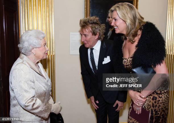 Britain's Queen Elizabeth II reacts as she greets musician Rod Stewart and wife Penny Lancaster during an award ceremony at the Royal Academy of Arts...