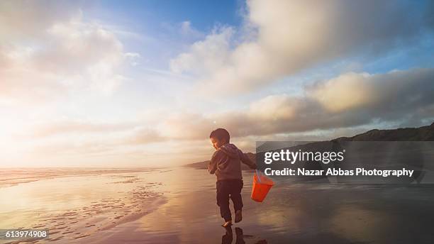 kid with bucket at beach. - child silhouette ocean stock pictures, royalty-free photos & images