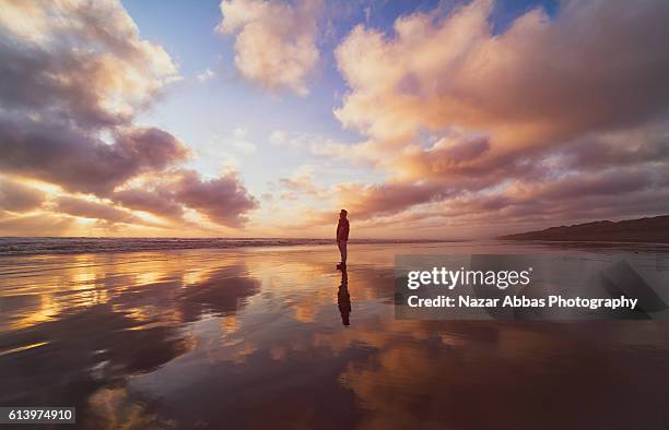 man standing on beach. - faith stock-fotos und bilder