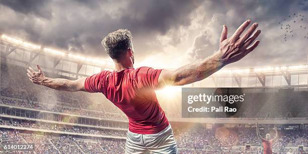 fußballer arms wide celebrating after scoring goal in match - fußballtrikot stock-fotos und bilder