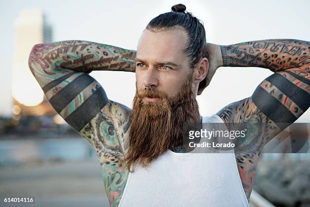 heavily tattooed bearded athletic alternative man stretching before a workout - strong hair 個照片及圖片檔