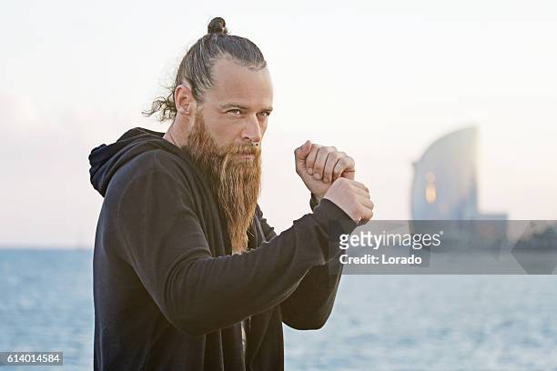 handsome bearded boxer shadow boxing by the sea - hair bun stockfoto's en -beelden