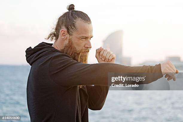 handsome bearded boxer shadow boxing by the sea - topknot stock pictures, royalty-free photos & images