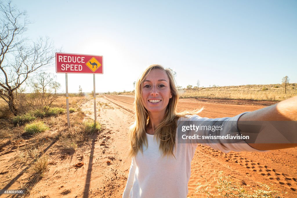 Selfie of young woman standing by Camel warning sign