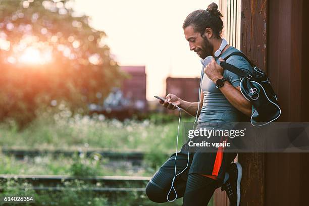 athletic man using his smart phone. - gym bag 個照片及圖片檔