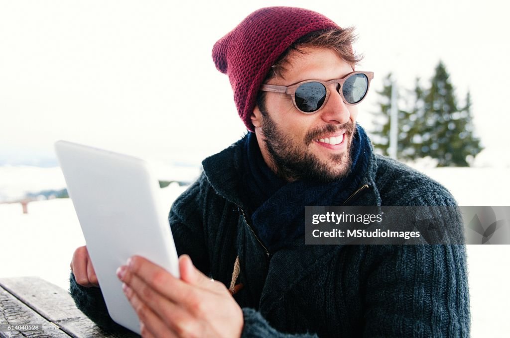 Smiling man using digital tablet.