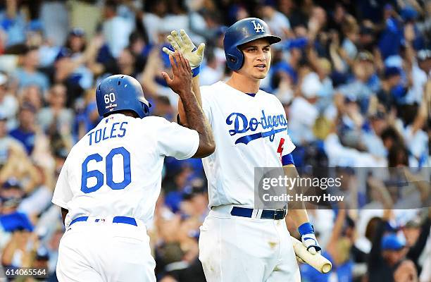 Andrew Toles of the Los Angeles Dodgers celebrates with Corey Seager after scoring on a single by Chase Utley in the eighth inning during game four...