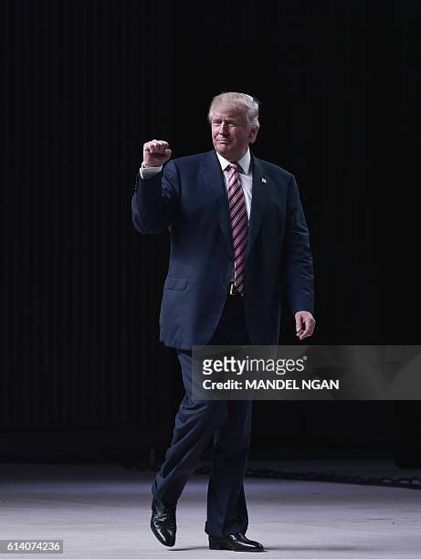 Republican presidential nominee Donald Trump clenches his fist as he makes his way off stage following a rally at Aaron Bessant Park on October 11,...