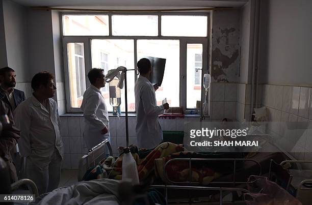 An Afghan doctor checks an x-ray of a wounded woman as she receives treatment at the Ali Abad hospital after an attack by gunmen inside the Karte...