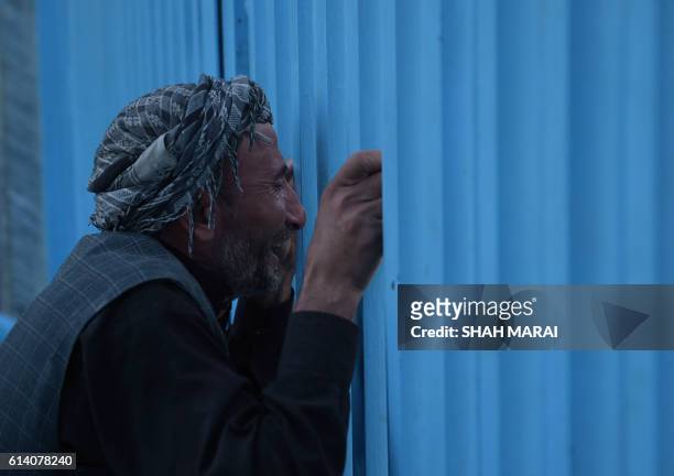 An Afghan man who lost his father in a gunmen attack weeps at the main gate of the Karte Sakhi shrine in Kabul on October 12, 2016. - Gunmen targeted...