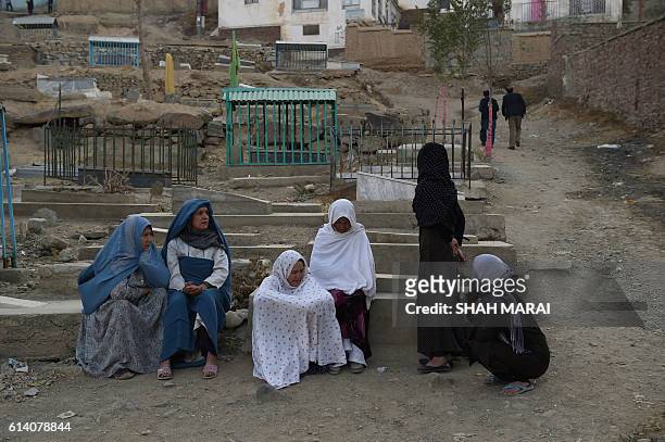Afghan women sit next to a grave yard near the Karte Sakhi shrine after an attack by gunmen inside the Karte Sakhi shrine in Kabul on October 12,...