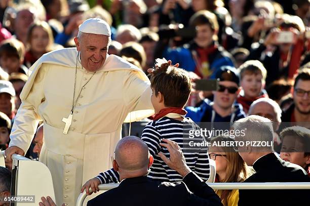Pope Francis greets a child aboard the popemobile during his weekly general audience in Saint Peter's square on October 12, 2016 at the Vatican. /...