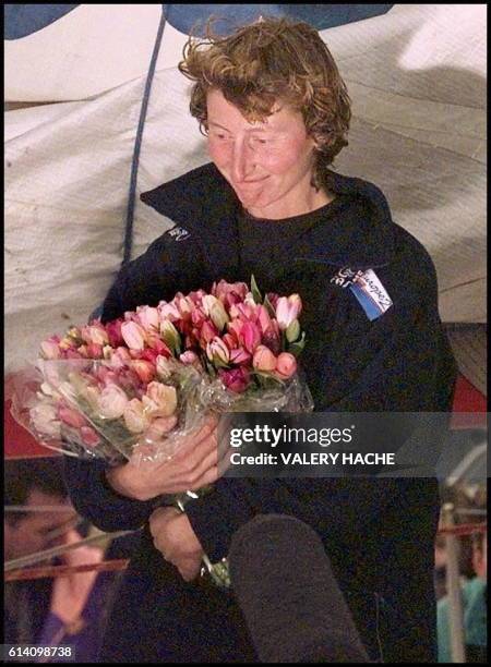 La navigatrice française Catherine Chabaud regarde la foule, un bouquet de fleurs à la main, le 23 mars aux Sables d'Olonne, après avoir franchit la...