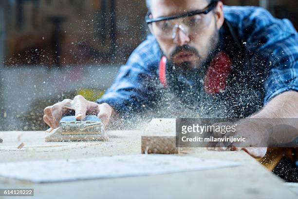 young handosme carpenter blowing off sawdust - sawdust stock pictures, royalty-free photos & images