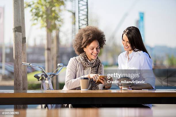 zwei schöne frauen trinken kaffee zu gehen - tablet alcohol stock-fotos und bilder
