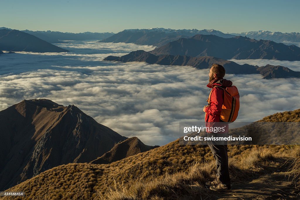 Hiker on moutain top contemplates view