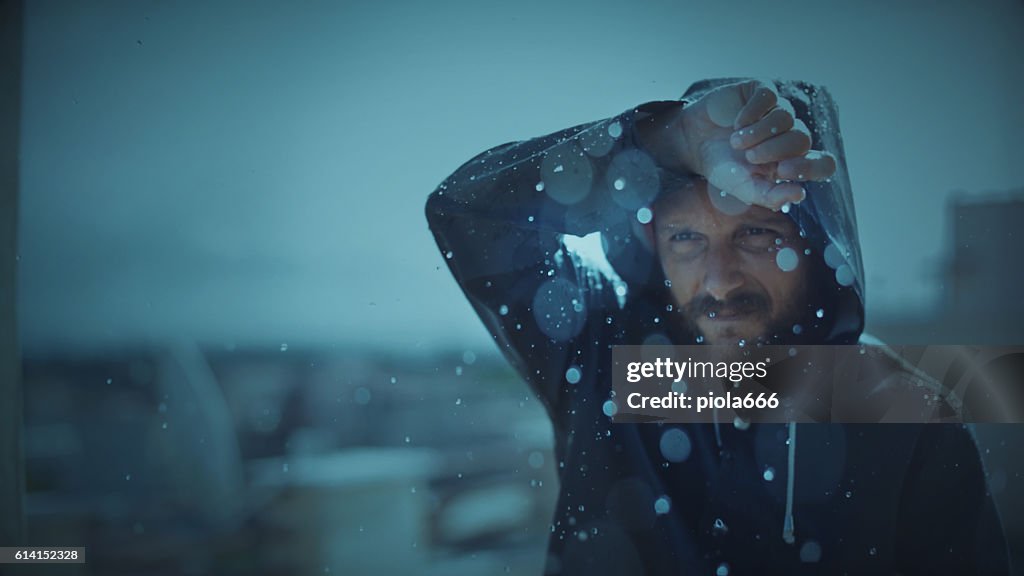 Man with raincoat under storm and heavy rain