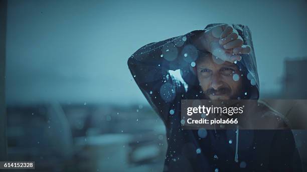 man with raincoat under storm and heavy rain - raincoat stockfoto's en -beelden