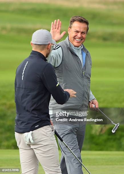 Entrepreneur Peter Jones high fives footballer Aaron Ramsey during the Hero Pro-Am at The Grove on October 12, 2016 in Watford, England.