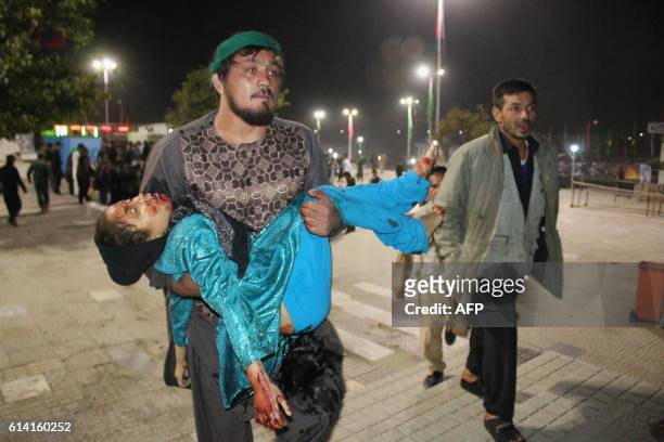 Graphic content / TOPSHOT - This photograph taken late on October 11, 2016 shows an Afghan man carrying a wounded girl after an attack by gunmen at...