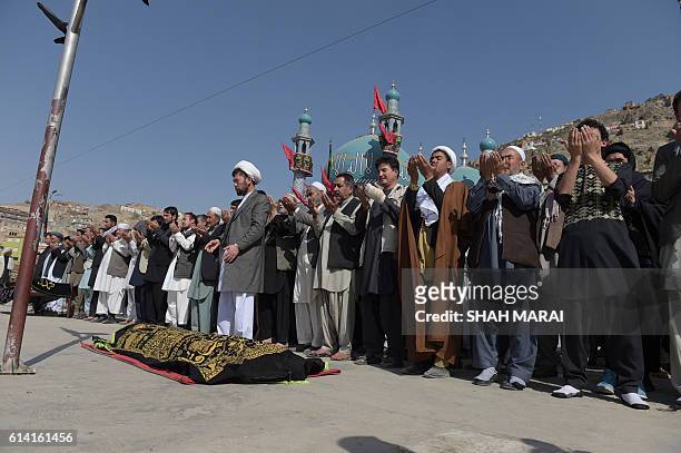 Afghan mourners offer funeral prayers for a victim in Kabul on October 12 who was killed in an attack by gunmen inside the Karte Sakhi shrine late on...