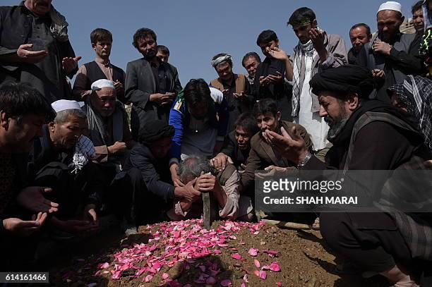 An elderly father mourns at the grave of his son in Kabul on October 12 after he was killed in an attack by gunmen inside the Karte Sakhi shrine late...