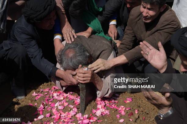 An elderly father mourns at the grave of his son in Kabul on October 12 after he was killed in an attack by gunmen inside the Karte Sakhi shrine late...
