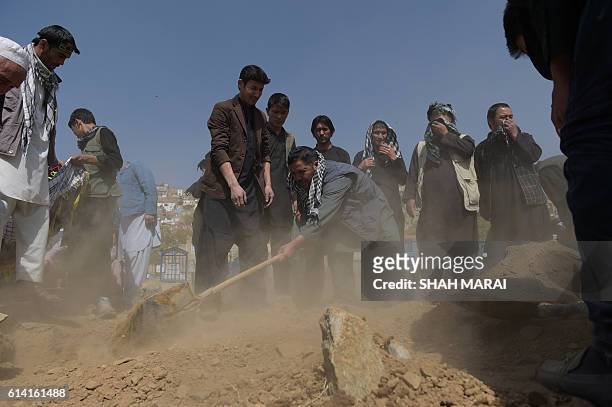 Afghan men bury a victim in Kabul on October 12 after he was killed in an attack by gunmen inside the Karte Sakhi shrine late on October 11. Grieving...