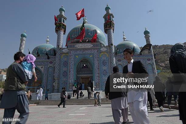 Afghan men walk in front of the Karte Sakhi shrine in Kabul on October 12 after an attack by gunmen late on October 11. Grieving worshippers on...