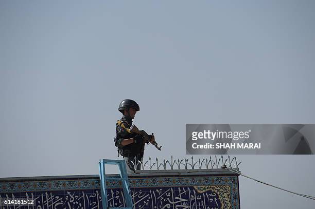 An Afghan policeman keeps watch inside the Karte Sakhi shrine in Kabul on October 12 after an attack by gunmen late on October 11. Grieving...