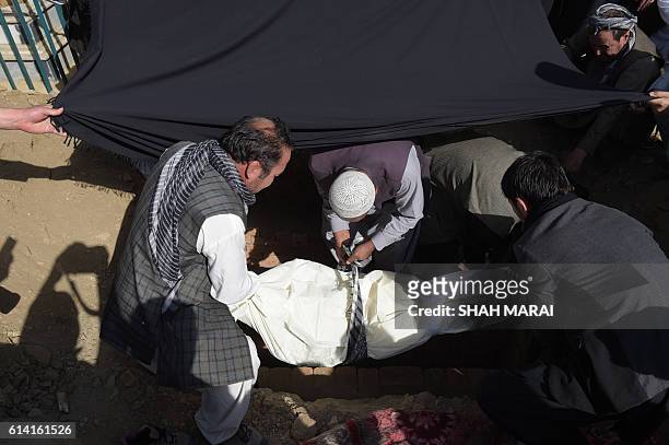 Afghan men bury a victim in Kabul on October 12 who was killed in an attack by gunmen inside the Karte Sakhi shrine late on October 11. Grieving...
