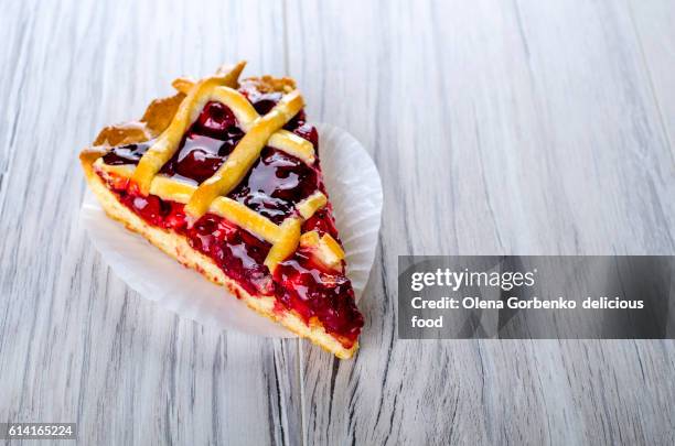 a piece of cherry pie on a wooden surface - obsttorte stock-fotos und bilder