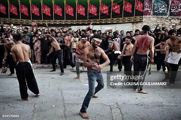 Shiite Muslim men, part of the migrant community currently living in Piraeus, near Athens, use chains and blades during a self-flagellation ritual to...