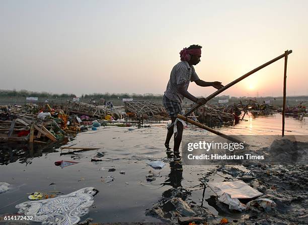 Locals scavenge for the remains of Goddess Durga idols after the immersion in the River Yamuna near ISBT, on October 12, 2016 in New Delhi, India....