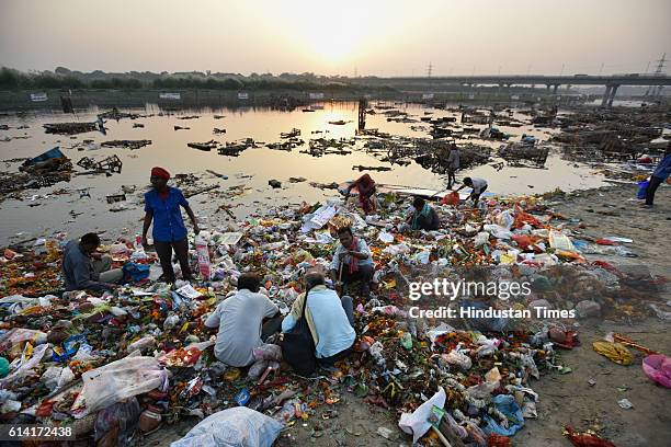 Locals scavenge for the remains of Goddess Durga idols after the immersion in the River Yamuna near ISBT, on October 12, 2016 in New Delhi, India....