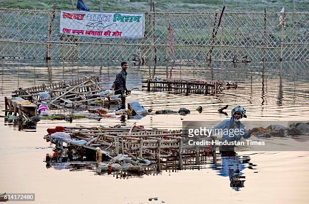 Locals scavenge for the remains of Goddess Durga idols after the immersion in the River Yamuna near ISBT, on October 12, 2016 in New Delhi, India....