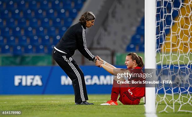 Head Coach Anouschka Bernhard of Germany gives team mate Tanja Pawollek of Germany a leg-up after losing the FIFA U-17 Women's World Cup Quarter...