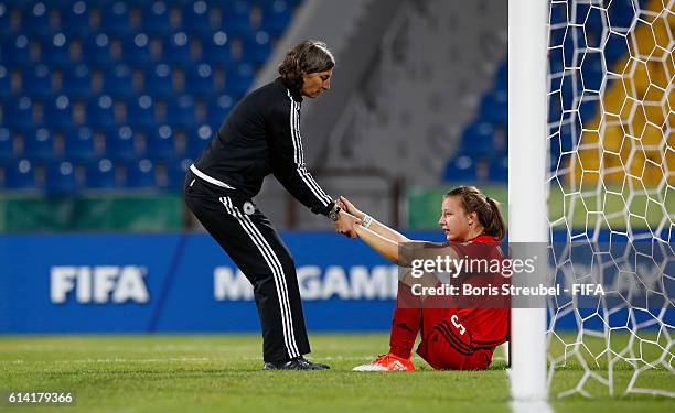 Head Coach Anouschka Bernhard of Germany gives team mate Tanja Pawollek of Germany a leg-up after losing the FIFA U-17 Women's World Cup Quarter...