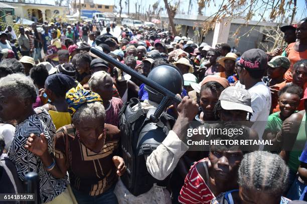 Haitian policeman tries tioo keep order while Hurricane Matthew victims wait for the delivery of food from the UN's World Food Programme in...