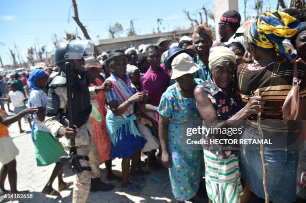 Haitian policeman tries to keep Hurricane Matthew victims in order as they wait to receive food from the UN's World Food Programme in...