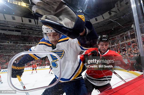 Patrik Berglund of the St. Louis Blues and Gustav Forsling of the Chicago Blackhawks chase after the puck by the boards during the season opener at...