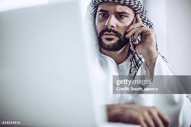 arab man in office on mobile - addiction mobile and laptop stockfoto's en -beelden