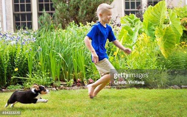 young boy children running with puppy dog on lawn - boy running with dog stock pictures, royalty-free photos & images