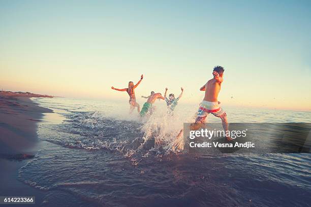 freunde laufen aufs meer - blurred running sunset stock-fotos und bilder