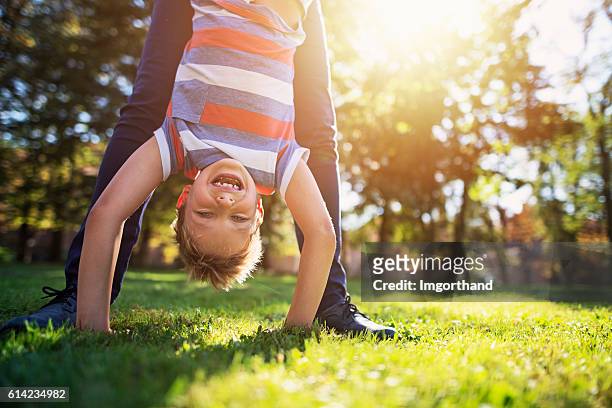 bambino che gioca con la madre nel parco - fare la verticale sulle mani foto e immagini stock