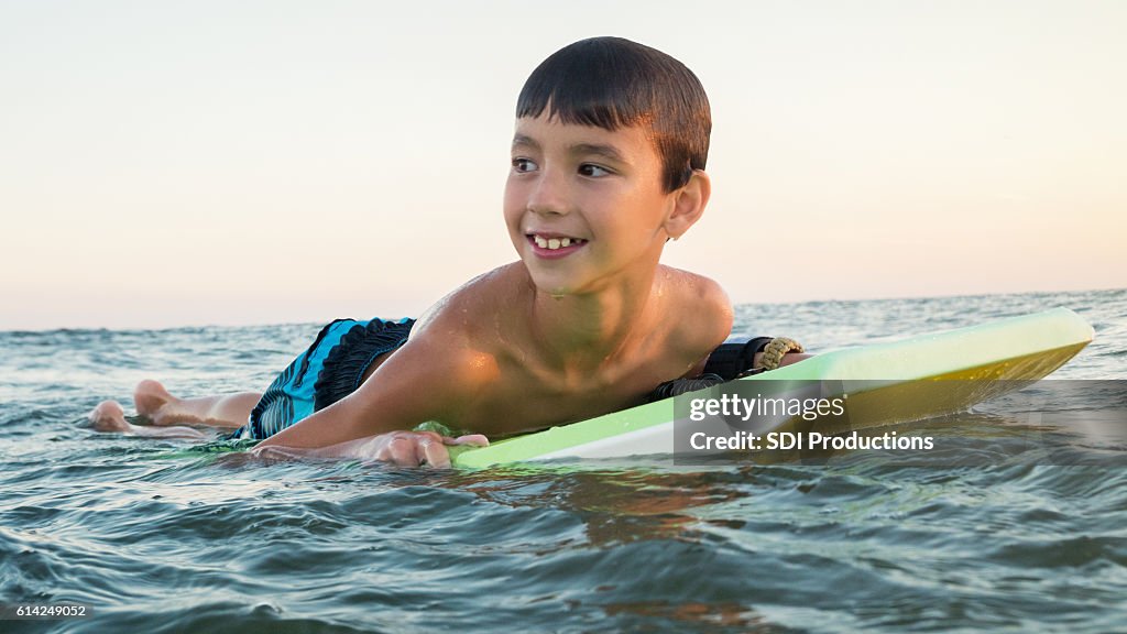 Cheerful boy uses body board in ocean