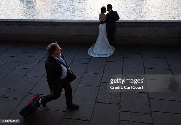 Man walks past as Charles Qian and his fiance Echo Li pose during a pre-wedding photography shoot opposite the Palace of Westminster on October 11,...